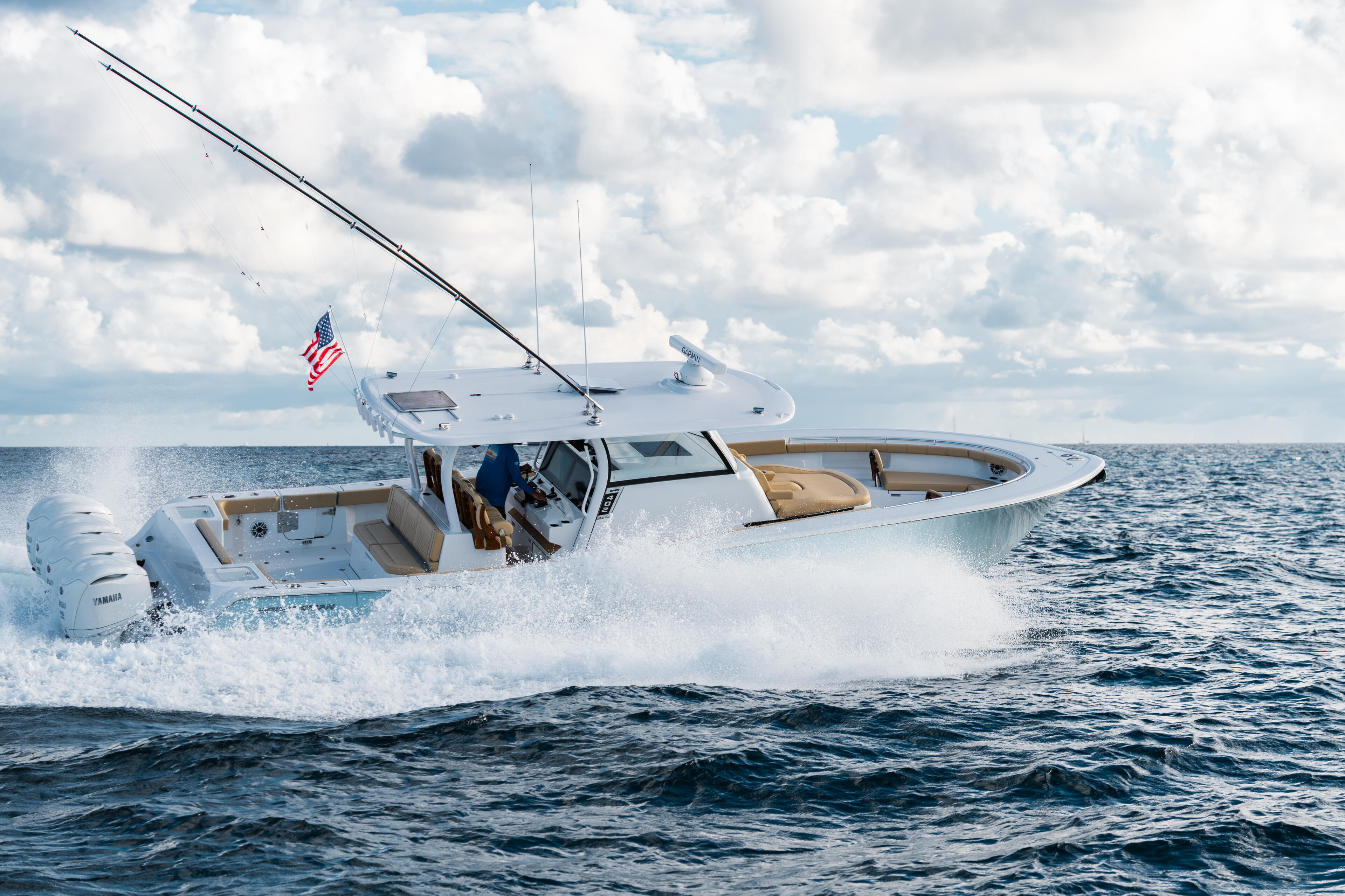 White sport fishing boat running at speed through ocean waves with American flag flying