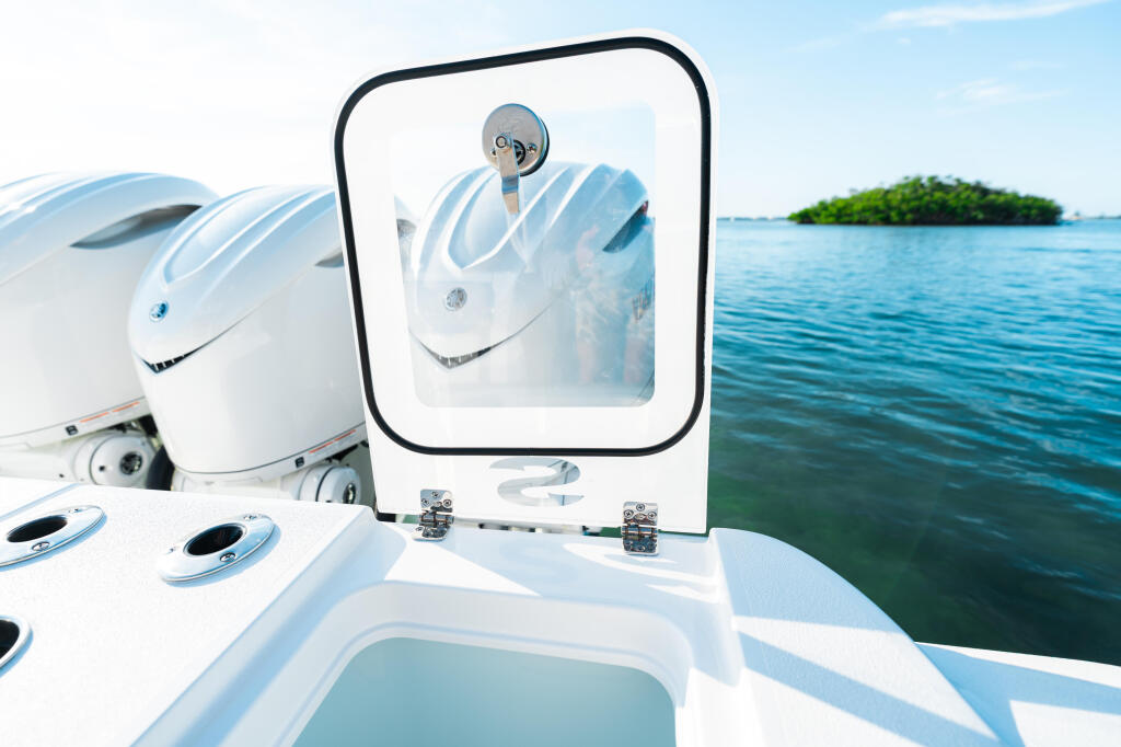 Helm station with circular mirror reflecting twin outboard engines and tropical island backdrop
