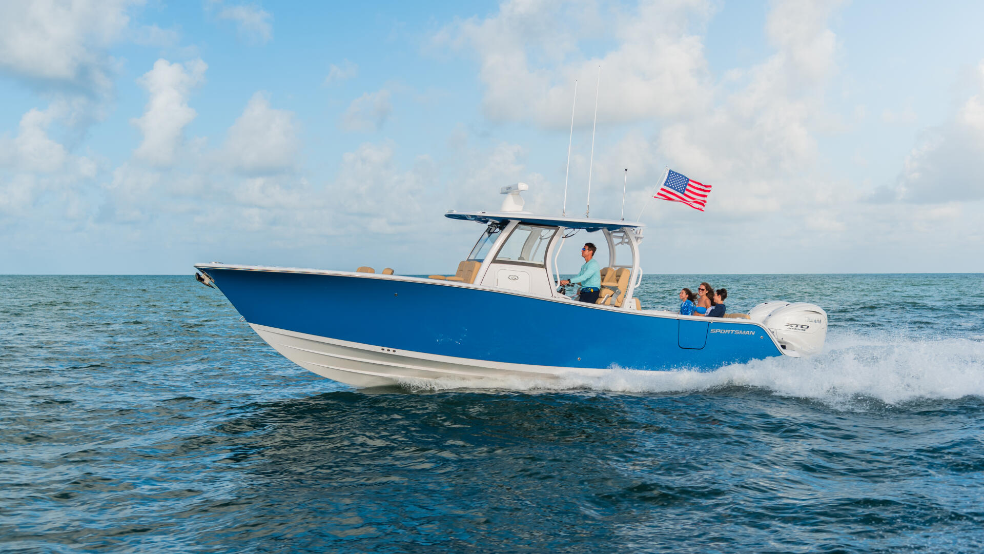 Blue and white center console boat running through shallow water with family aboard and American flag flying
