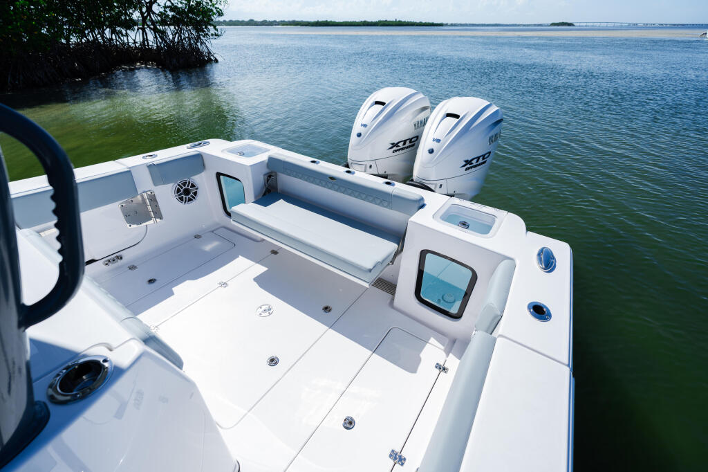 Open center console boat with dual Yamaha outboard engines docked in calm shallow water near mangroves