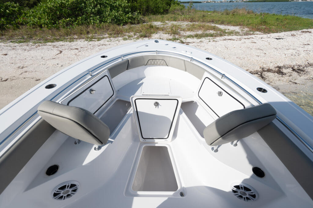 Center console boat beached on sandy shore with open bow seating and storage compartments