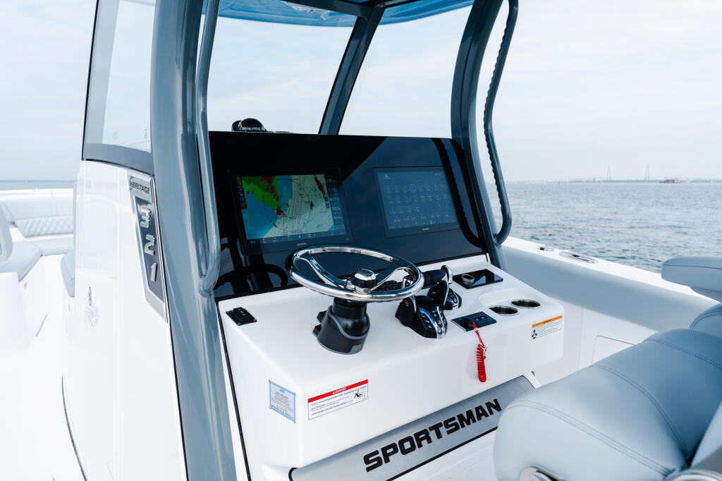 Modern boat helm with dual screens, steering wheel, and control panel under blue canvas top