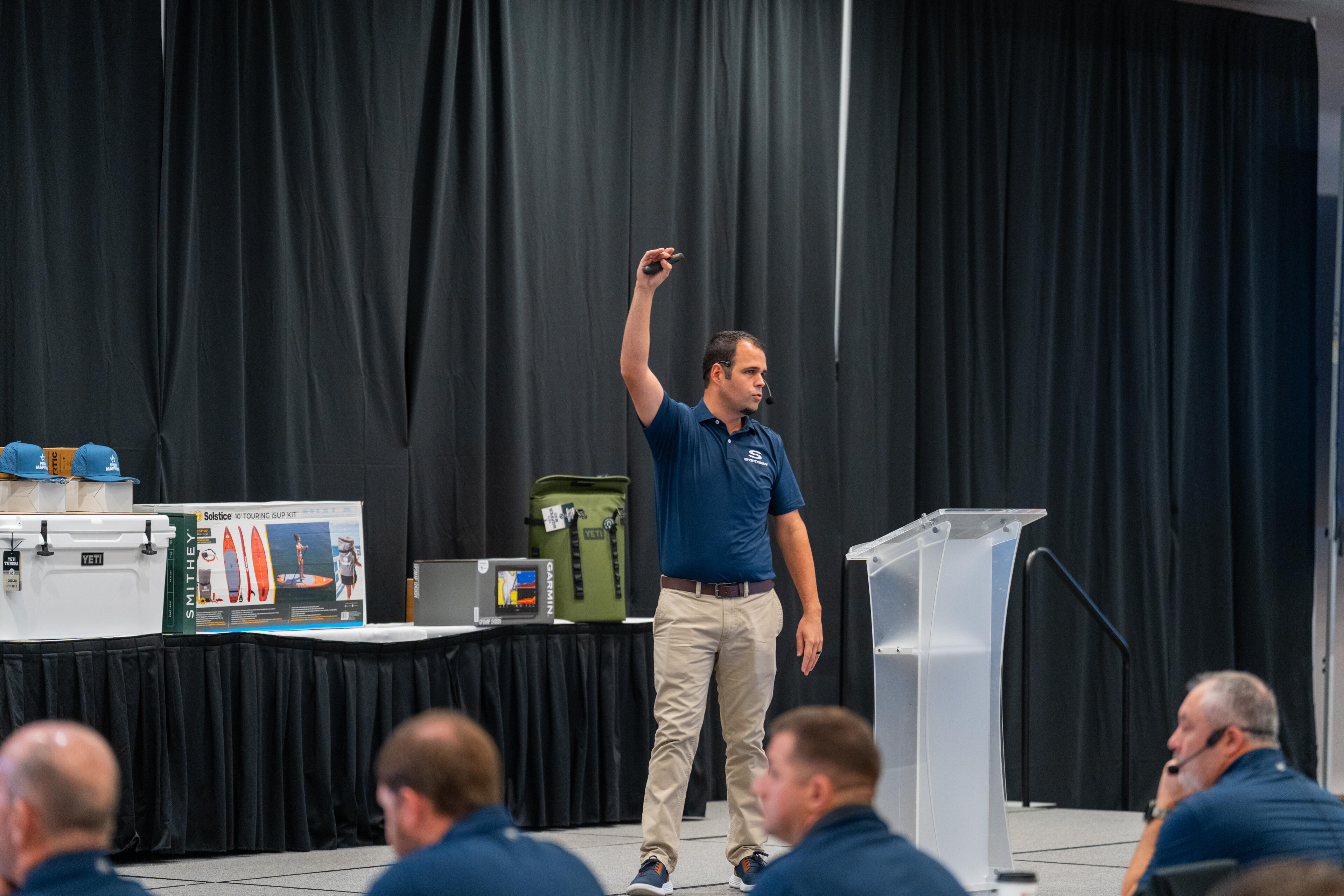 Salesman presenting boat features and accessories to an indoor audience at a trade show or dealership event