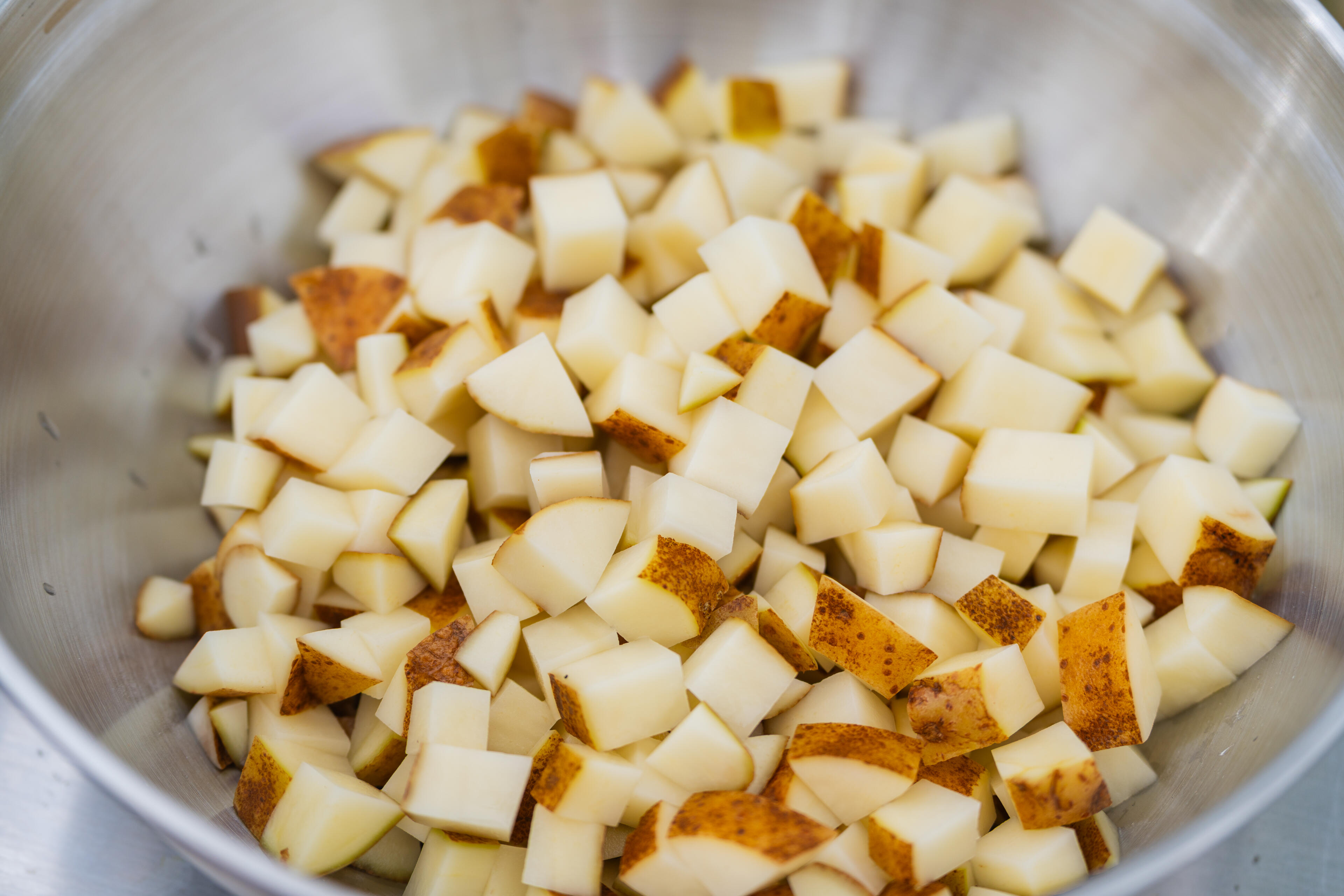 Diced potatoes with browned edges in a stainless steel pot