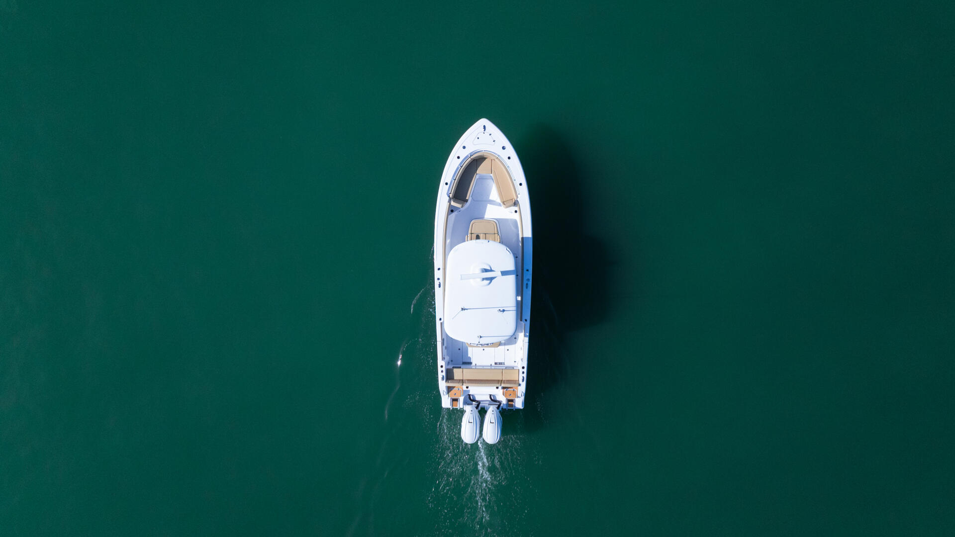 White sport fishing boat anchored in shallow turquoise water, shot from directly above