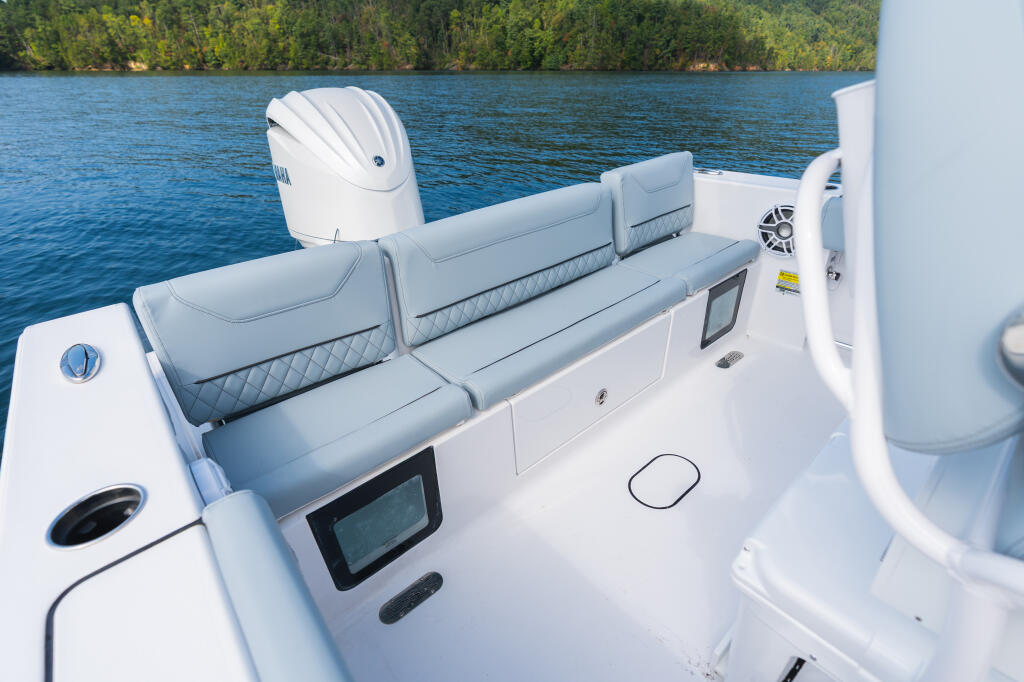Rear seating area of center console boat with gray upholstered bench seats and outboard engine