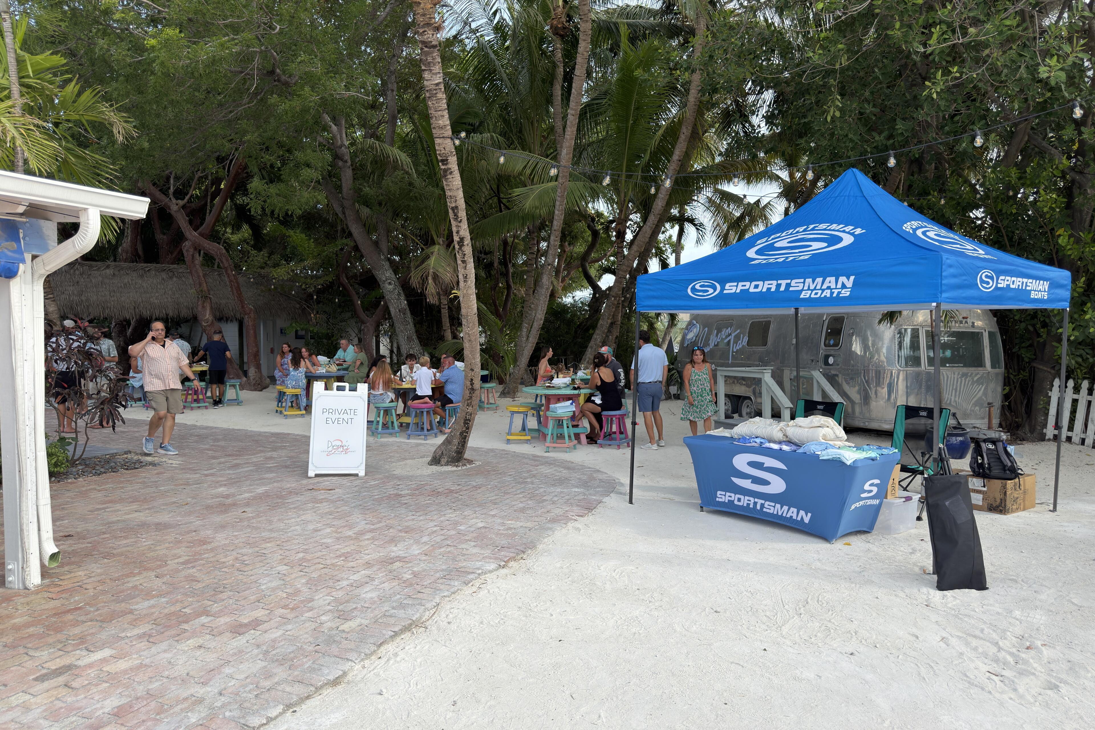 Sportsman Boats branded tent and display at a beachside community event with families gathered under palm trees