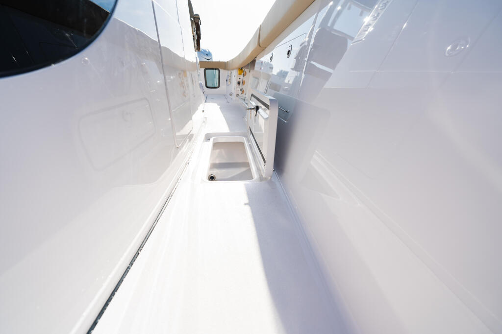Narrow starboard side deck of white boat with cabin door and small window visible