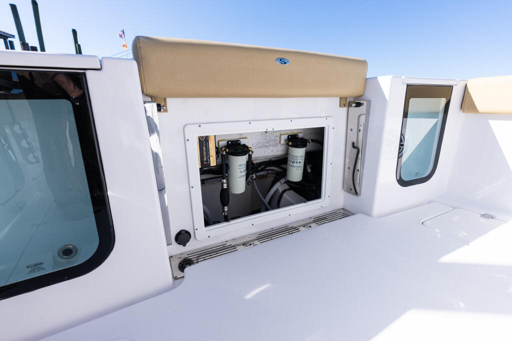Open engine compartment revealing mechanical systems, filters, and plumbing on center console boat