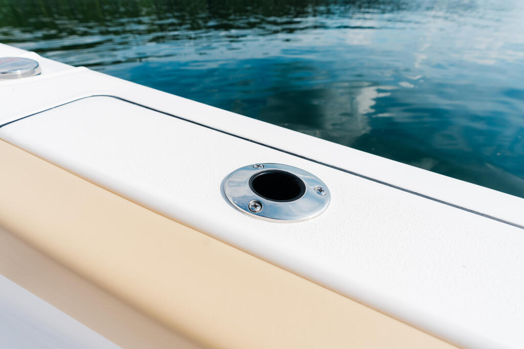 Boat gunwale with polished chrome through-hull fitting and tranquil blue water beyond