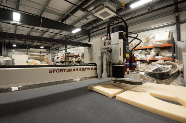 Sportsman Boats manufacturing facility with boat hulls and components in production, industrial equipment, and storage shelving