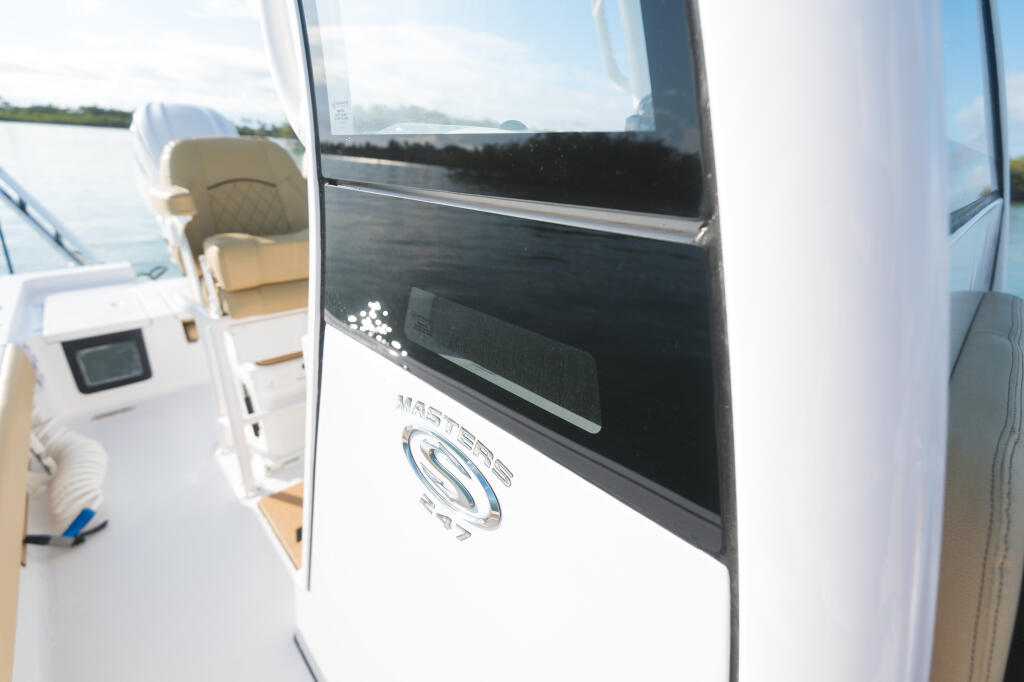 Open cabin door on white boat with helm controls and water view visible