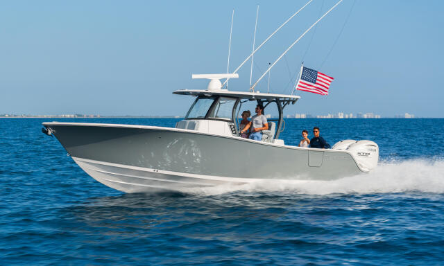A white center console boat with hard-top running at speed with couples aboard and an American flag flying