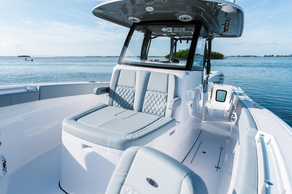 Modern white center console boat with hard-top canopy and gray quilted seating on calm blue water