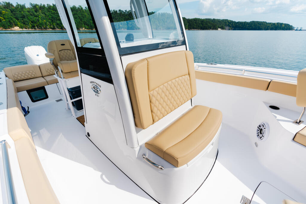 Tan leather seating and white deck with hardtop cabin on Heritage 251 boat, forested shoreline across calm waters