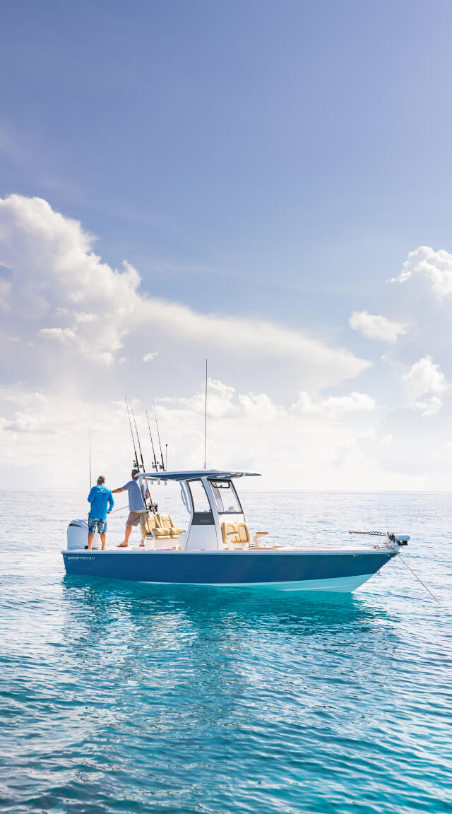 Two anglers on a blue and white center console boat anchored in clear turquoise water
