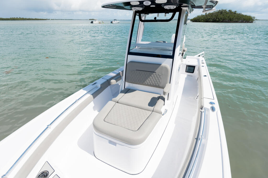 Bow chaise lounge and helm seating on a white center console boat anchored in shallow turquoise water