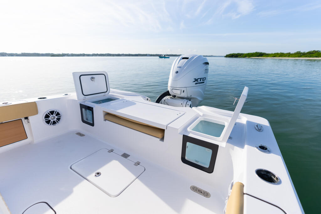 Stern deck of a white center console boat with electronics displays, overhead hatch, and outboard engine