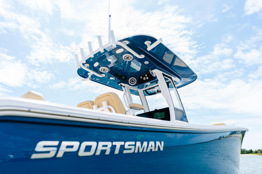 Blue Sportsman center console boat with hard-top and tan seating viewed from water level against cloudy sky