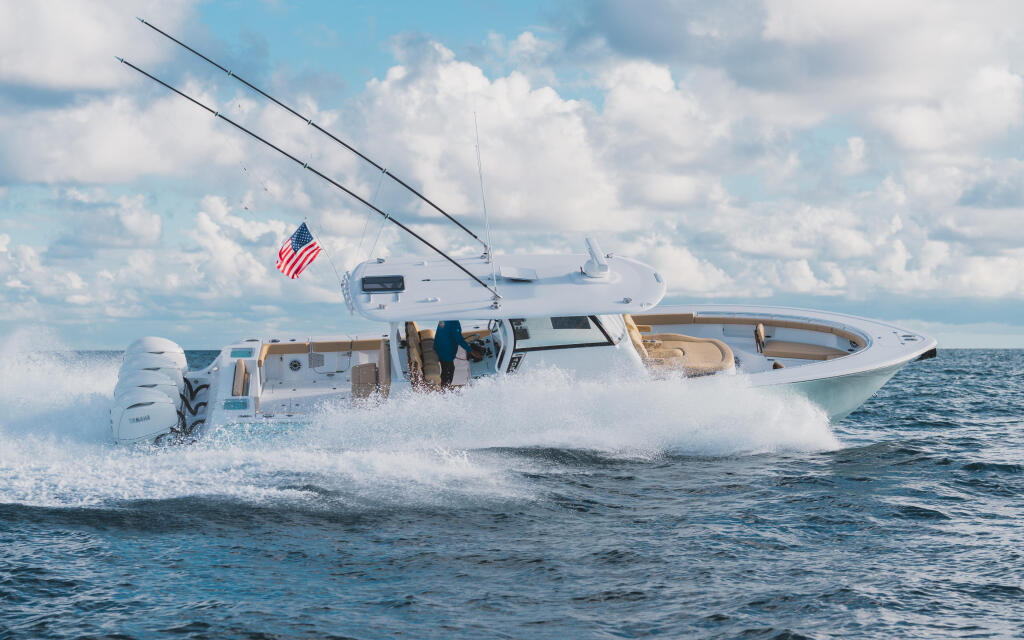 White center console boat running through offshore waves with American flag and twin outboard engines visible