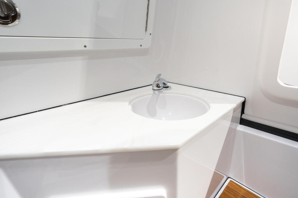 Clean white cabin galley with round sink and chrome faucet