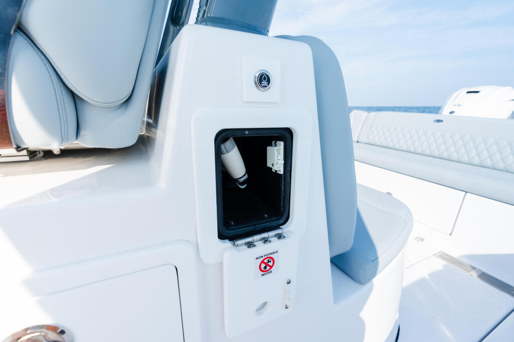 Open storage compartment with life jacket and equipment mounted on white boat console