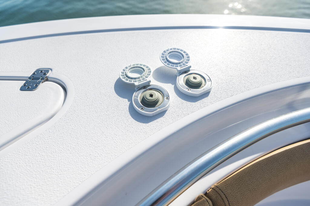 Boat deck detail showing anchor controls and recessed cleats on white fiberglass hull