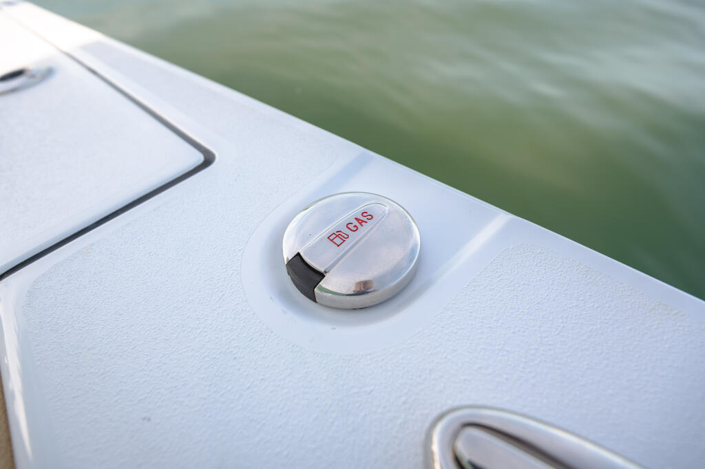 Close-up of dual fuel fill caps on white boat deck with calm green water in background