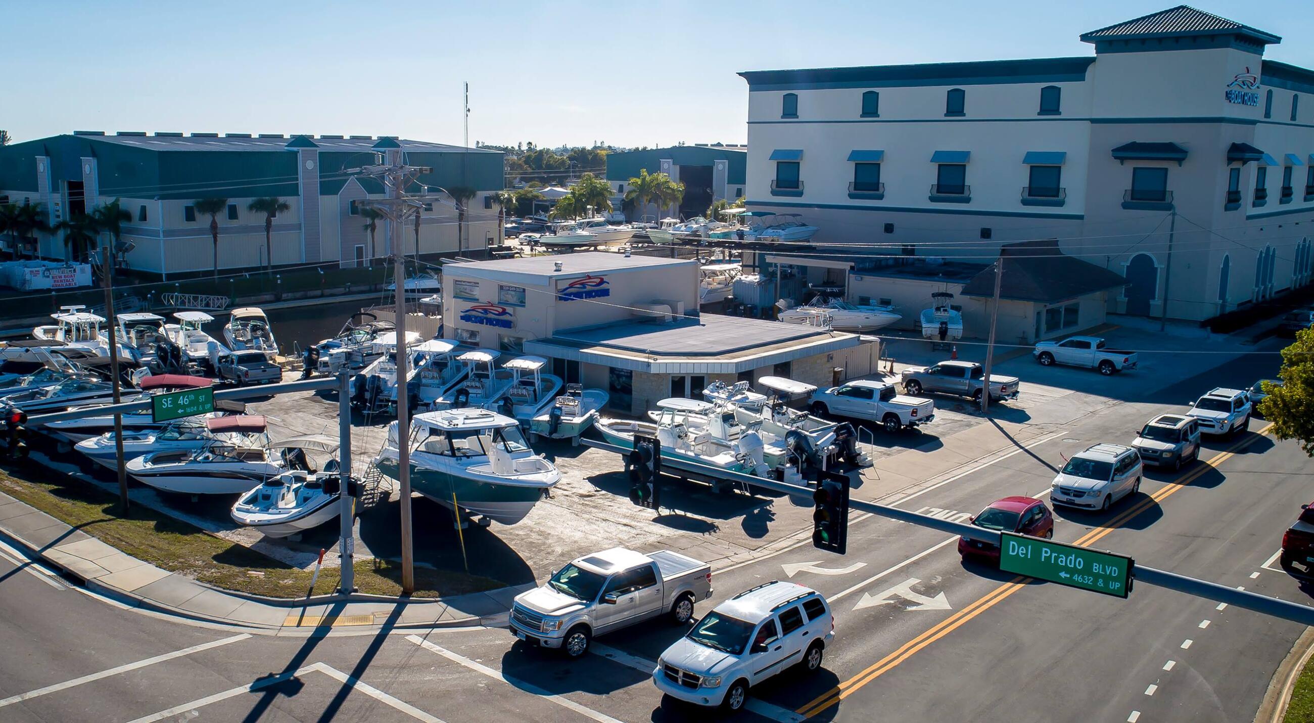 Aerial view of a marina facility with boats docked, service building, and parking lot in Cape Coral