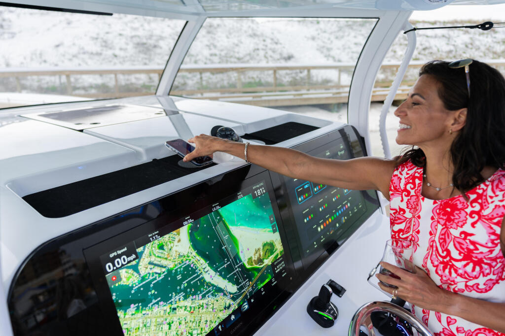 Woman at the helm operating advanced multifunction displays showing coastal navigation and weather data