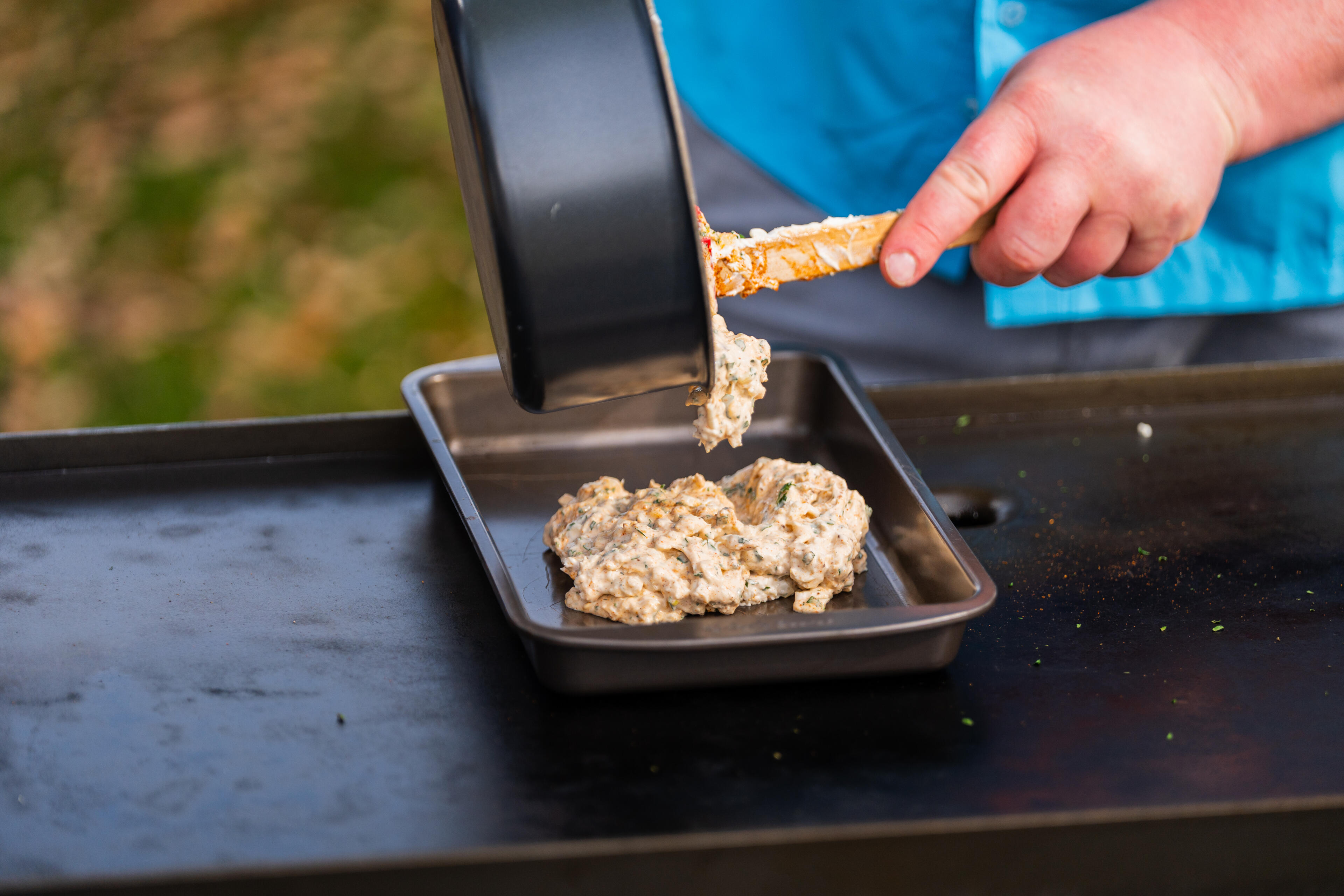 Child's hand spooning crab cakes from a black tray onto a boat deck