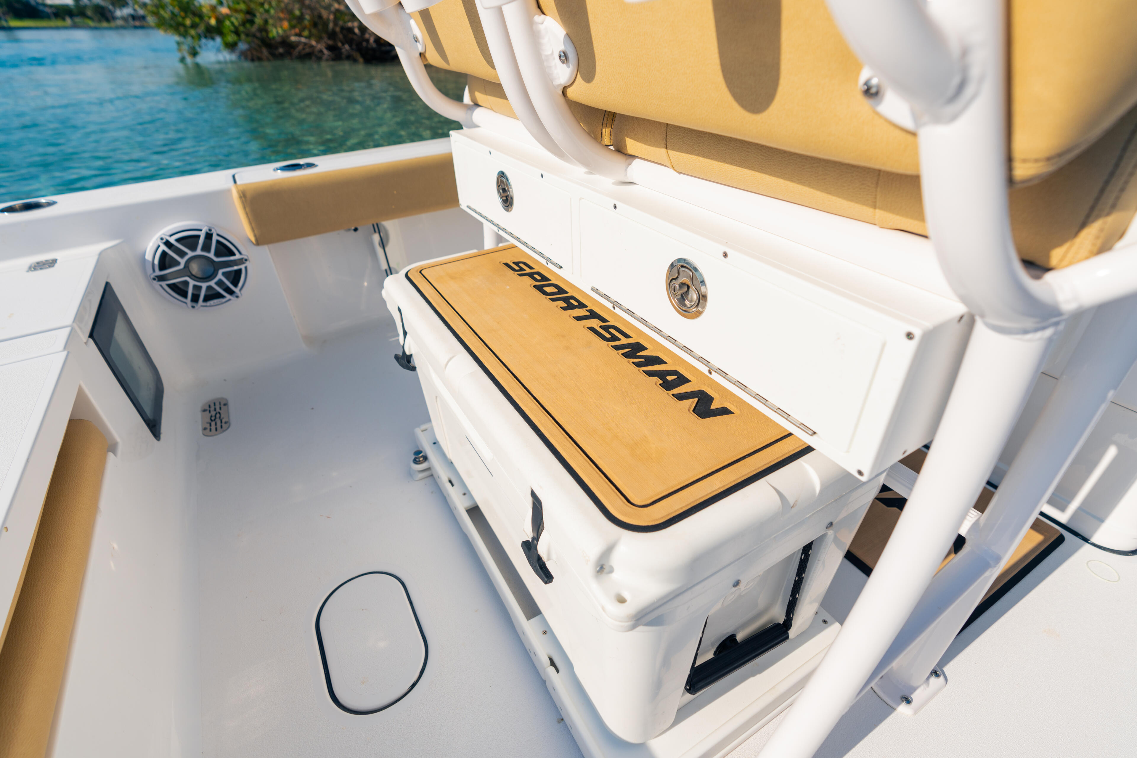 Starboard side deck of a white and gold boat with cooler and equipment storage near calm turquoise water