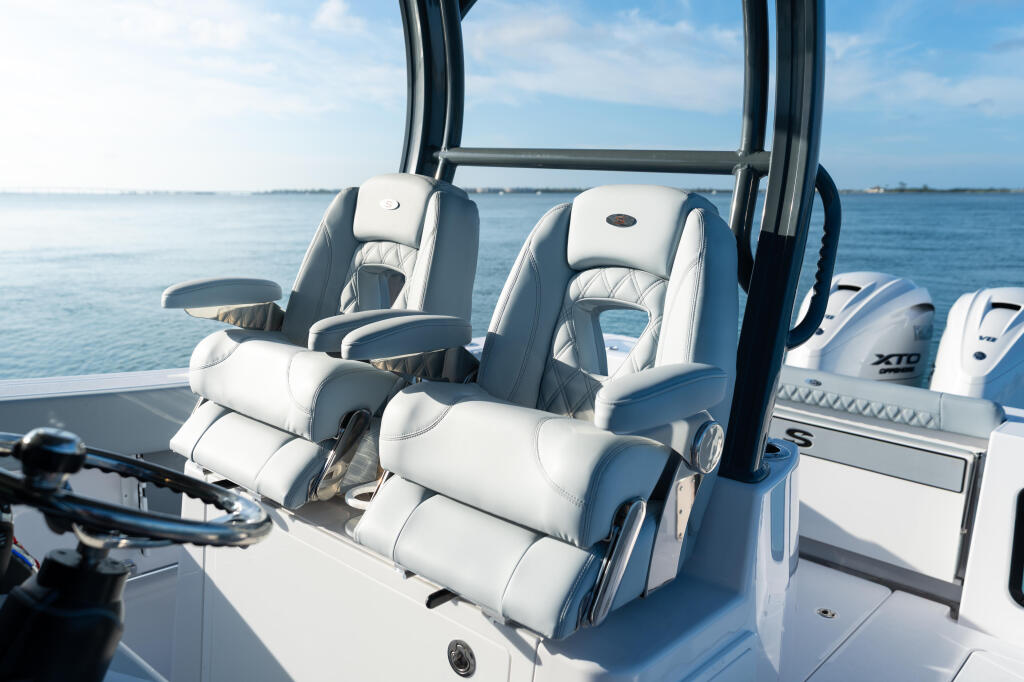 Luxurious white leather dual captain's seats with a black hard-top frame overlooking open water