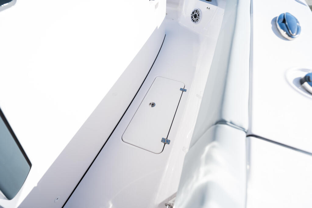 Overhead view of white fiberglass boat gunwale with storage compartment and cleats
