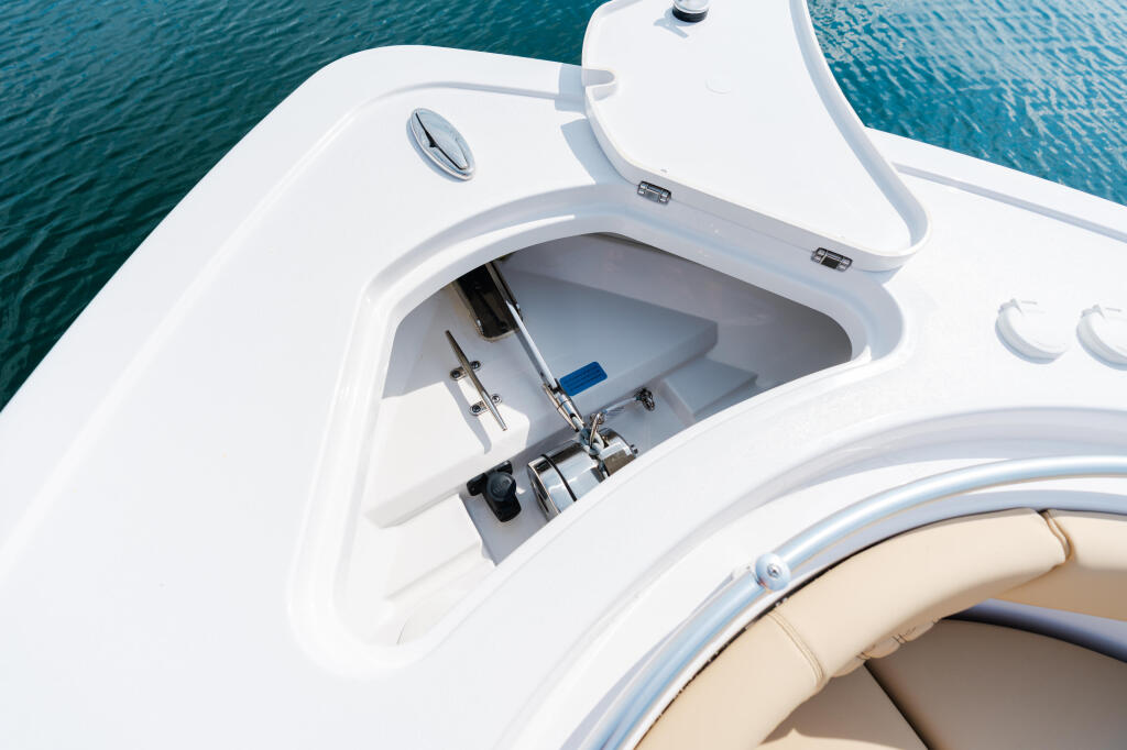 Open storage compartment on white boat console with helm visible and blue water beyond