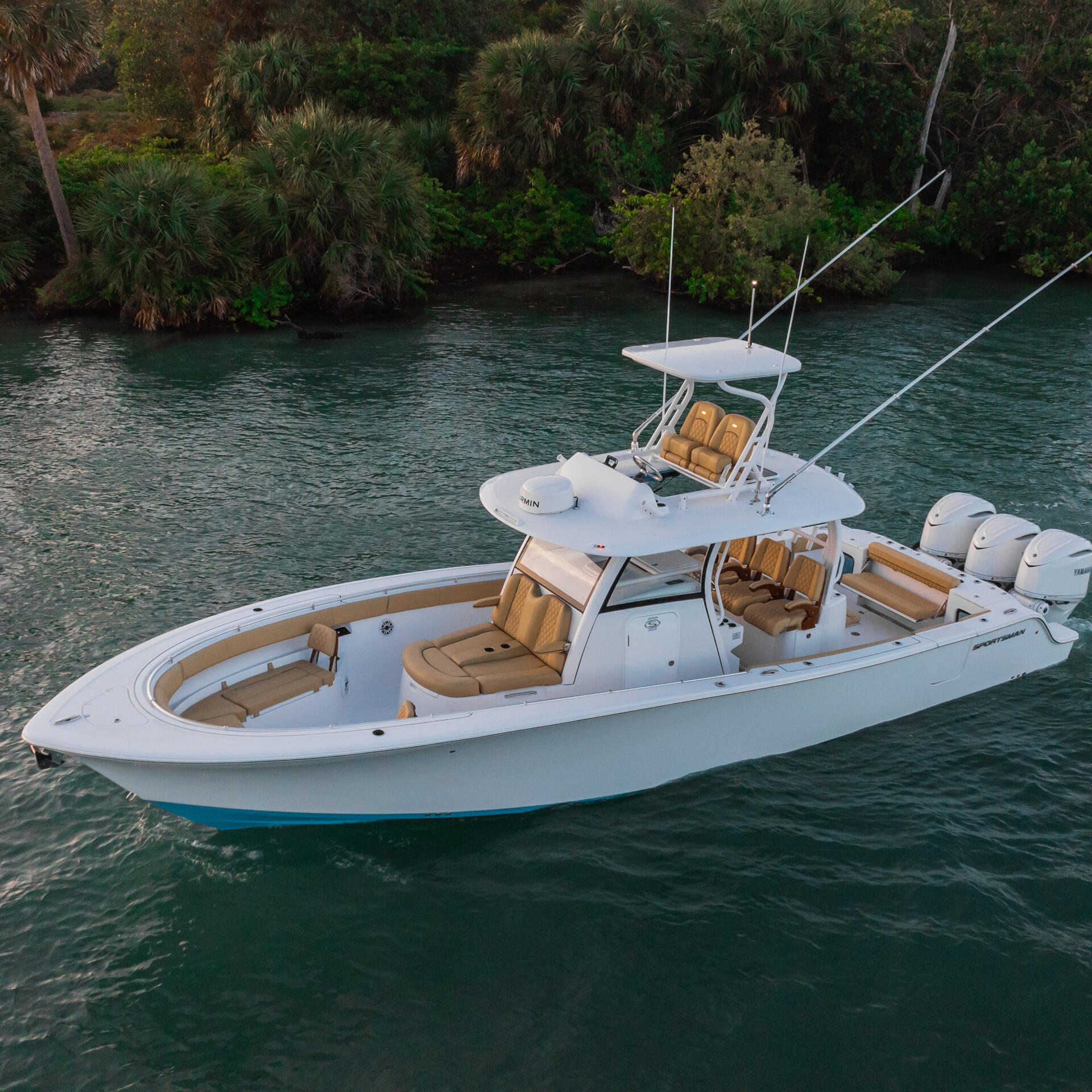 White sport fishing boat with tan seating and dual outboard engines anchored in clear turquoise water near mangrove shoreline