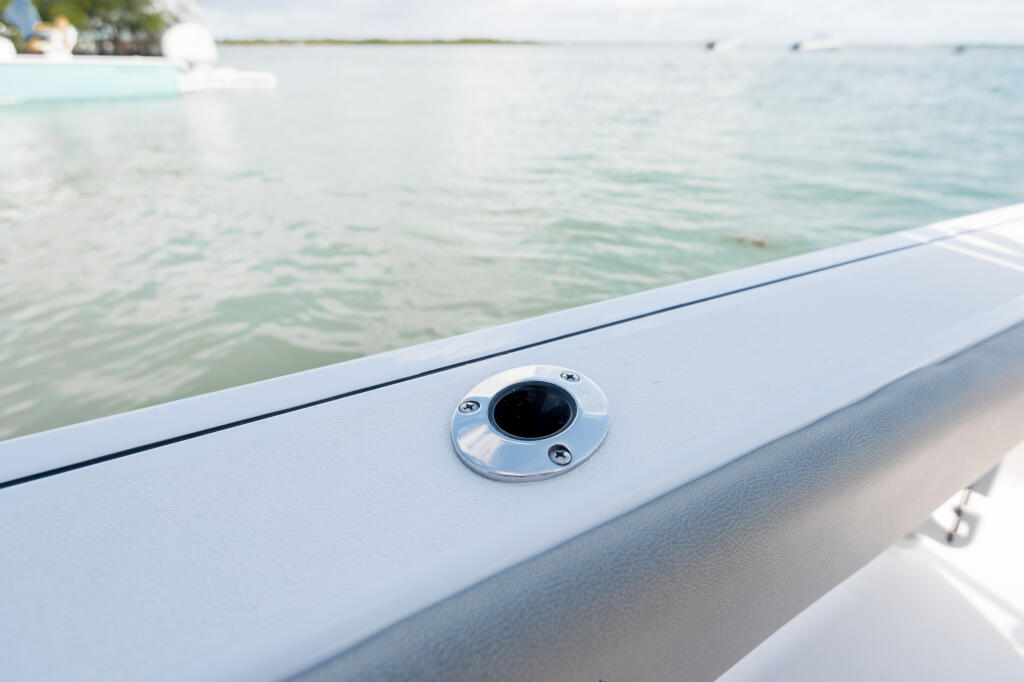 Flush-mount gunwale rod holder detail on boat gunwale overlooking calm turquoise water