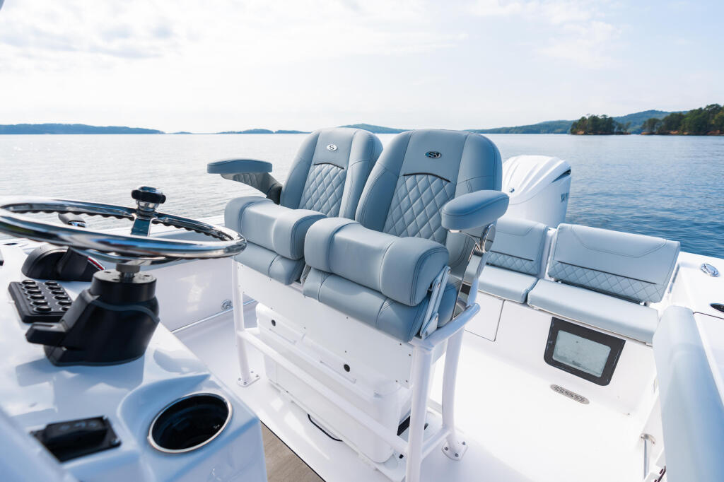 Premium dual-seat console with quilted upholstery and flip-up bolsters on a center console boat at rest on calm lake water