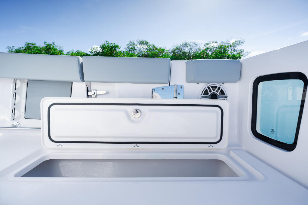 Overhead view of boat's starboard side showing livewell, window, seating, and helm controls with clear blue sky