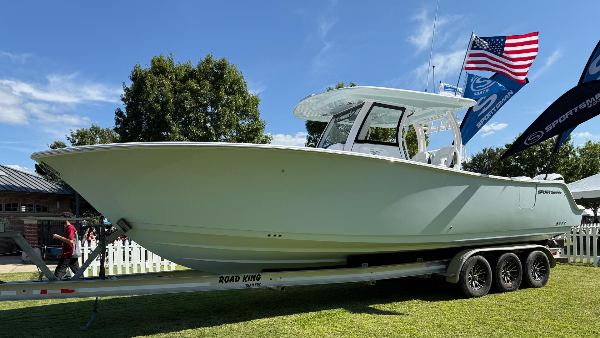 Sage green fishing boat with hard-top and white railings on Road King trailer at waterfront display
