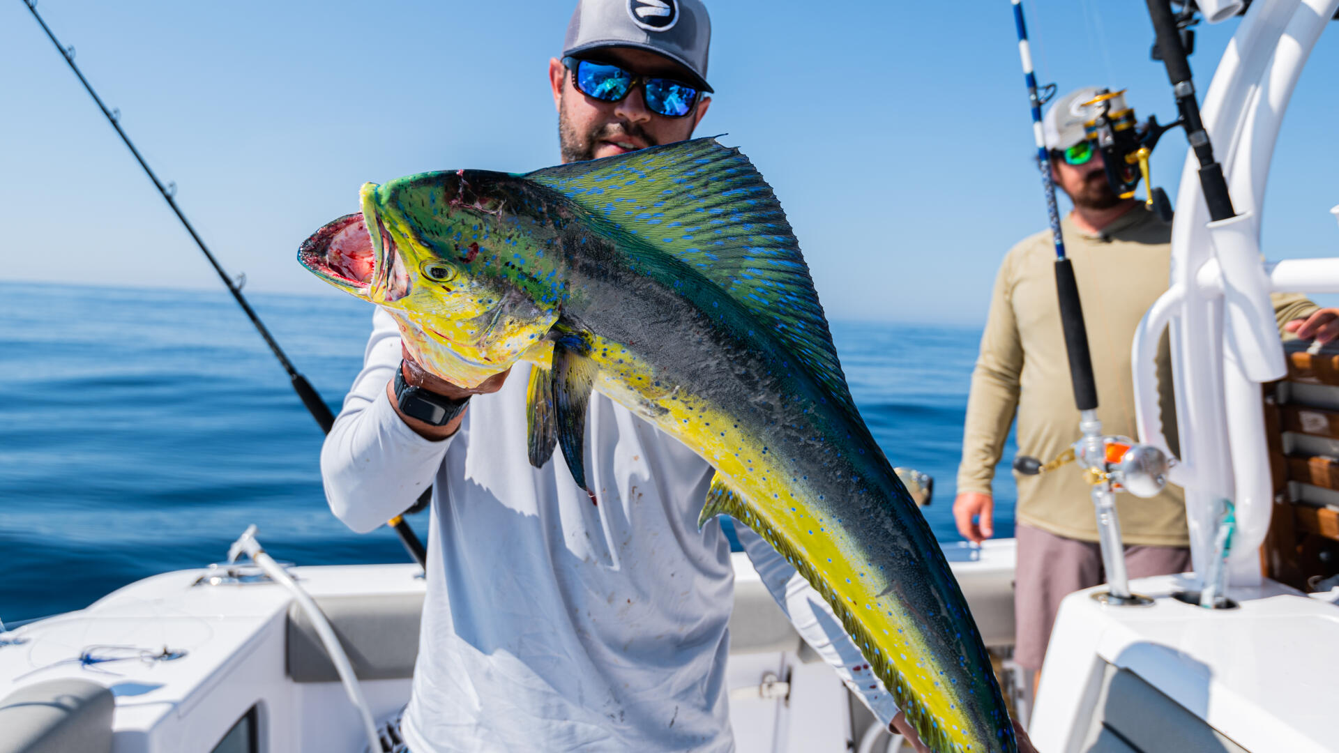 Angler holding a large mahi-mahi fish on an offshore fishing charter boat