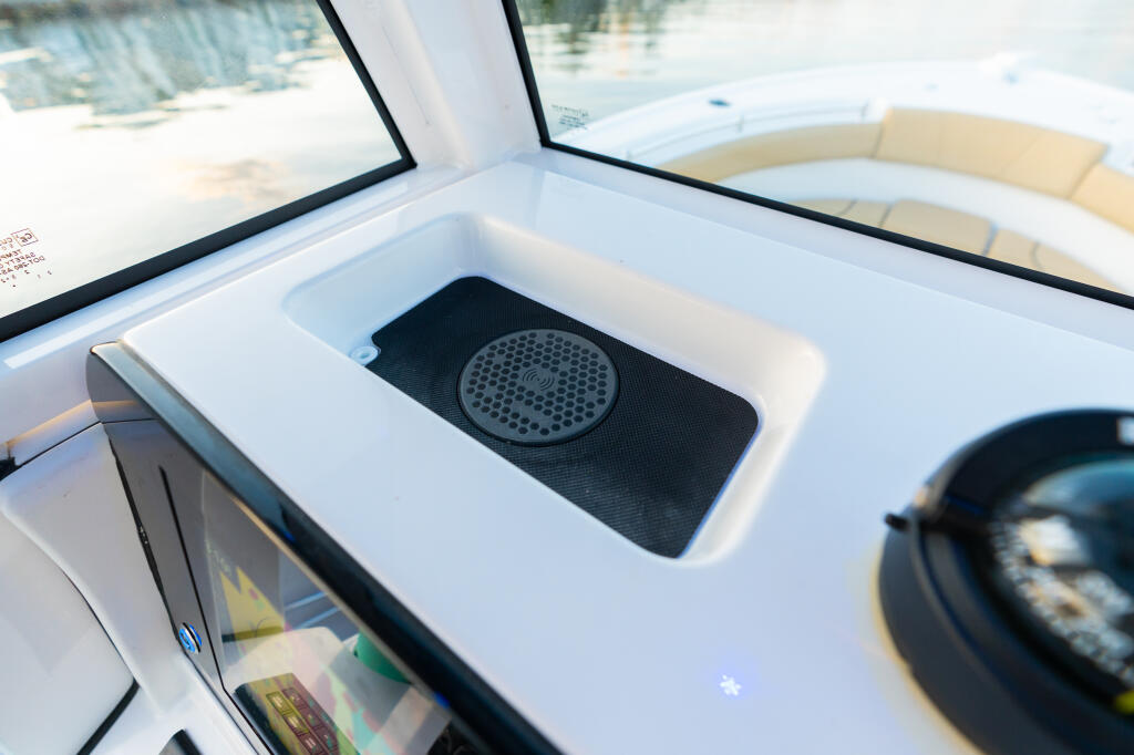 Wireless phone charger pad mounted in center console of boat with open hatch and windshield visible