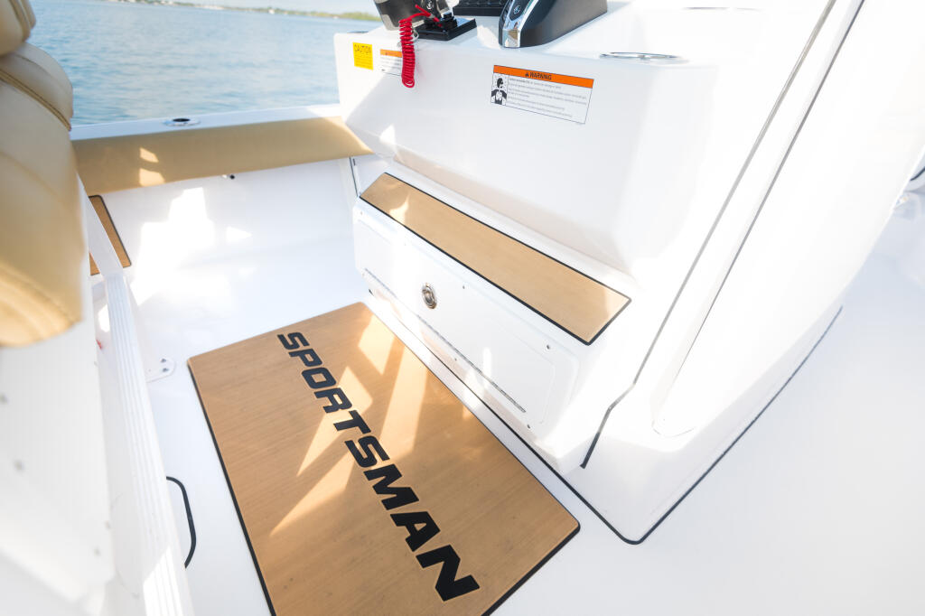 Sportsman boat cockpit with teak flooring, storage compartments, and helm controls visible on a sunny day