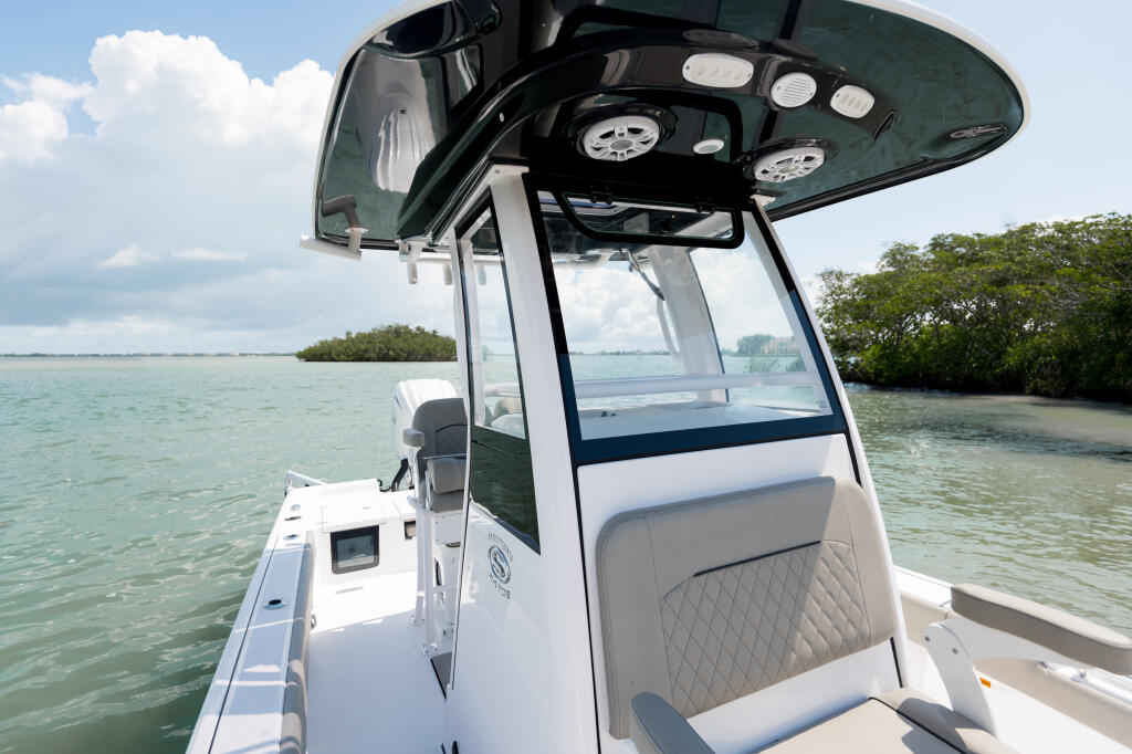 Hard-top helm console with dual gauges and windshield on a center console bay boat in shallow coastal waters