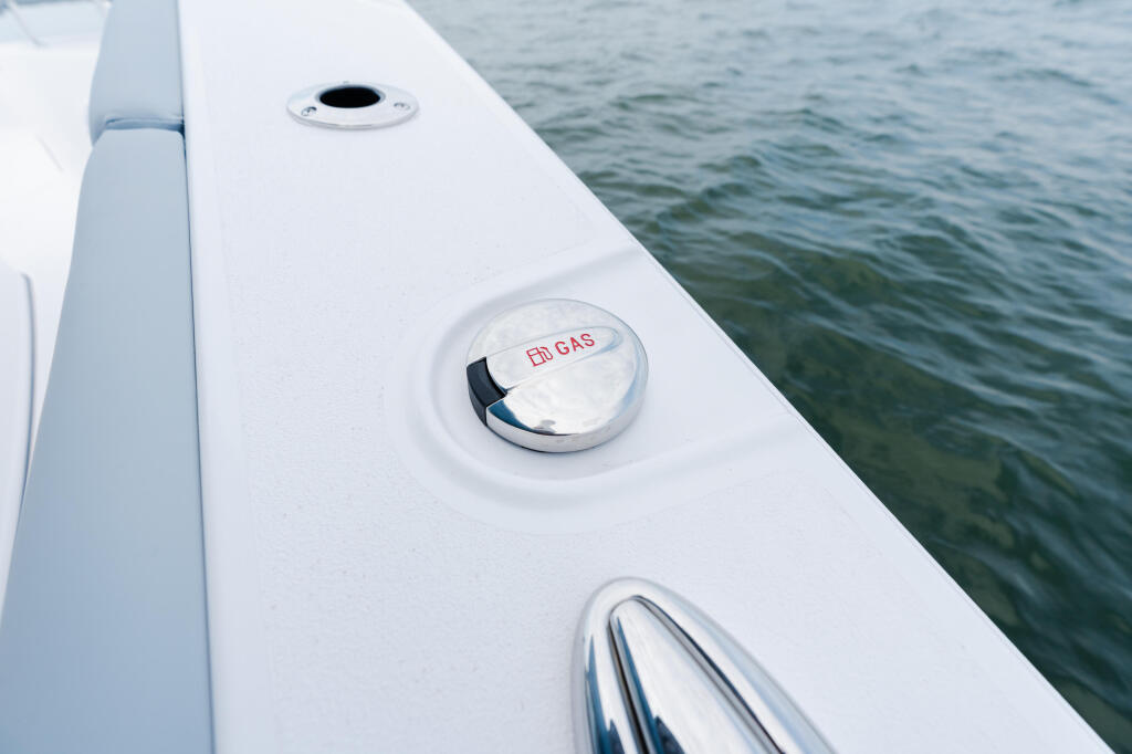 White boat gunwale with fuel gas cap and deck fittings over open water