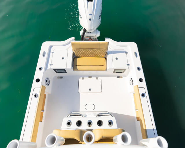 Aerial view of a white and gold center console boat with seating and storage in turquoise water