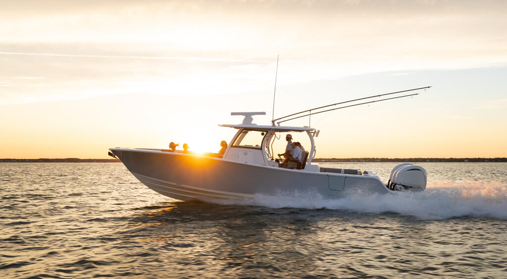 Center console fishing boat running through shallow water at golden sunset with passengers aboard