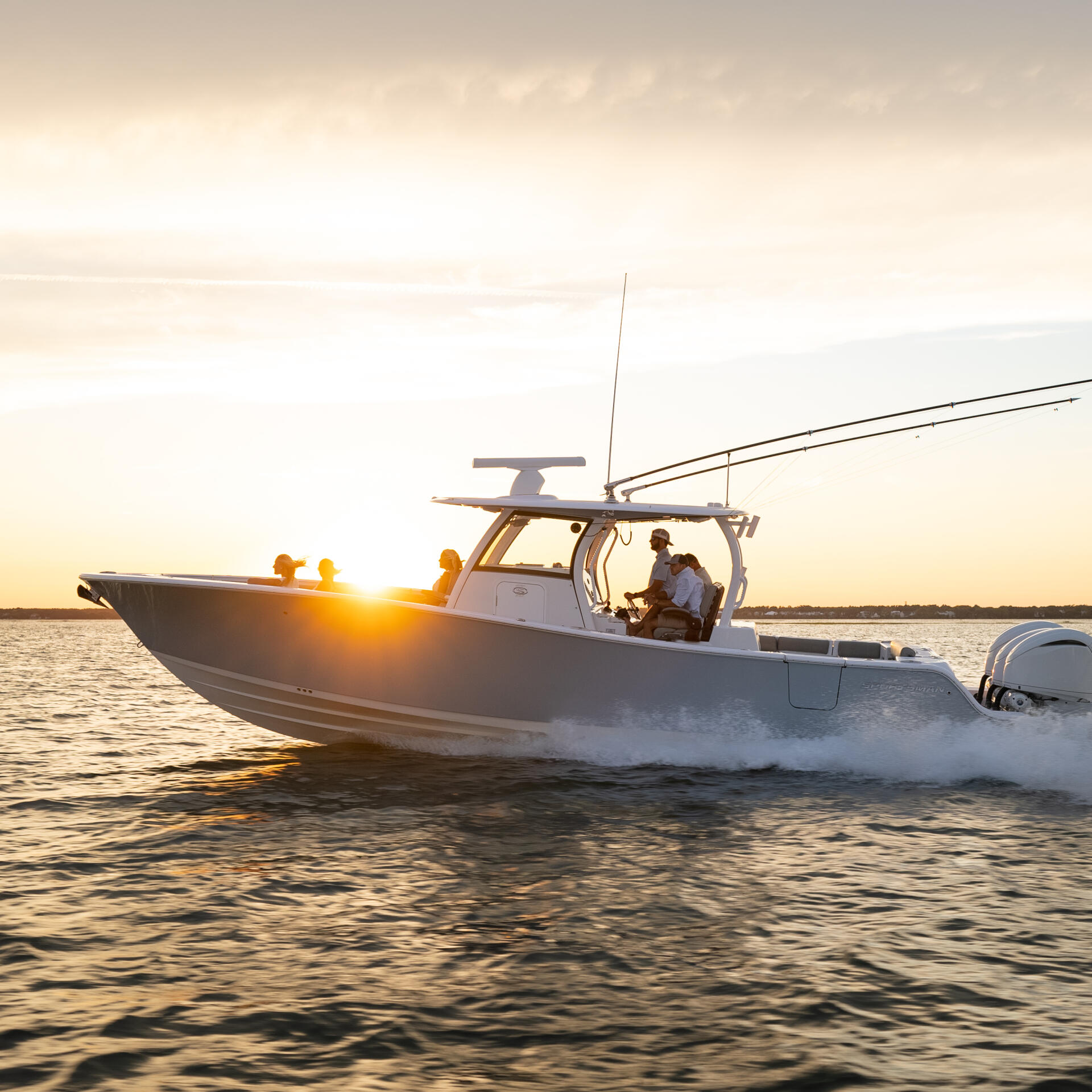 Center console fishing boat running through shallow water at golden sunset with passengers aboard