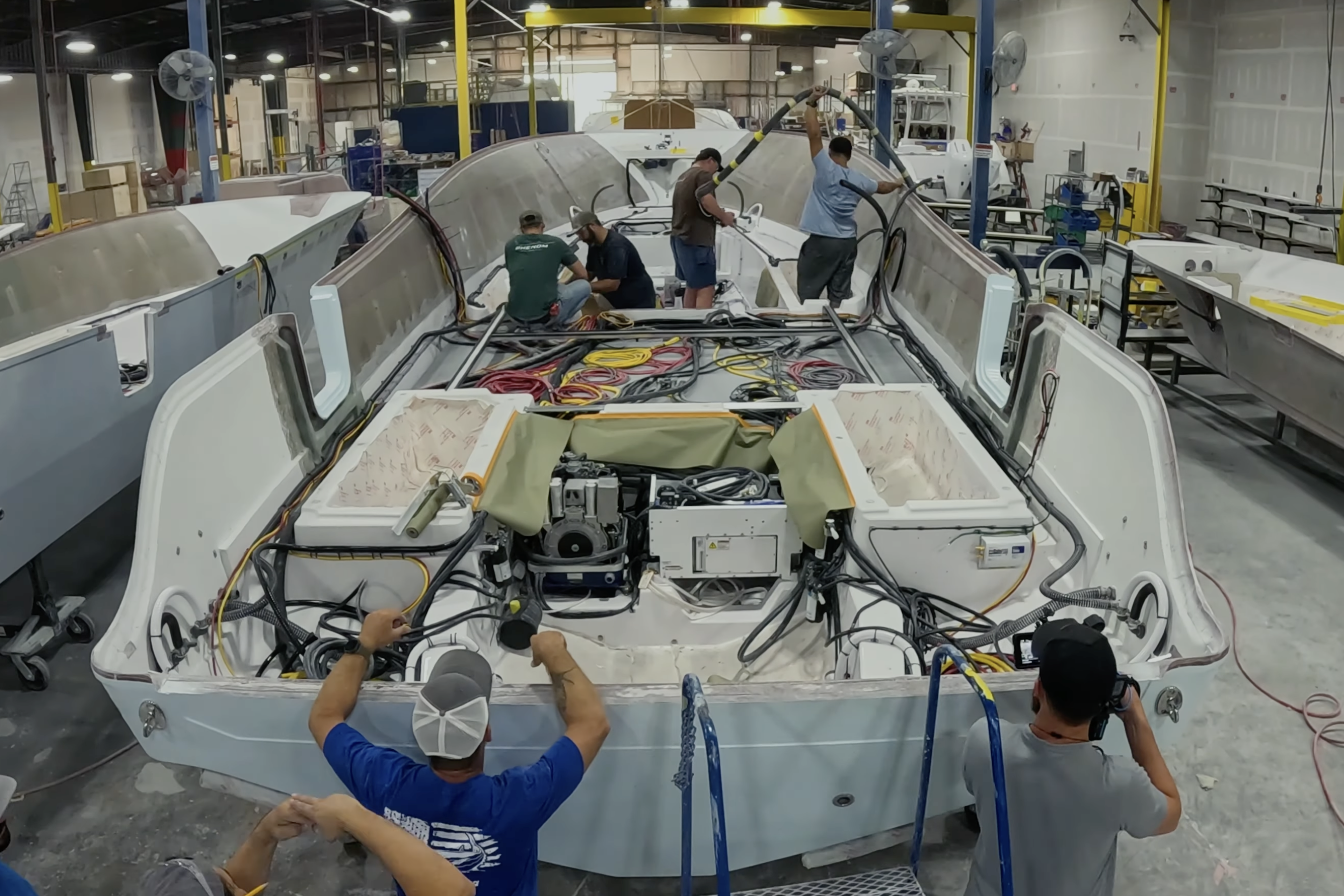 Boat manufacturing facility with workers assembling a sportfish boat hull during production