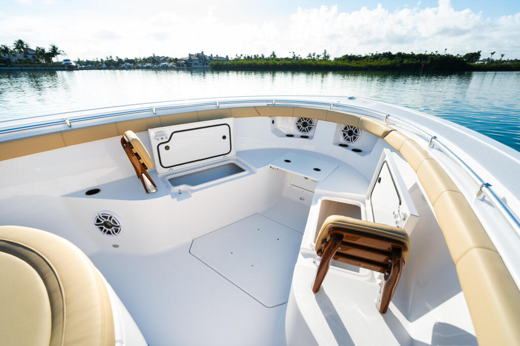 Spacious open-air boat deck with tan cushioned seating, white interior, and waterfront mangrove backdrop